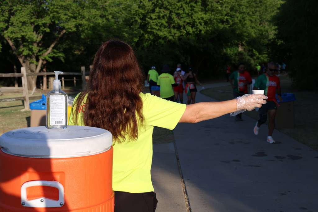 Volunteer at water stop passing cup